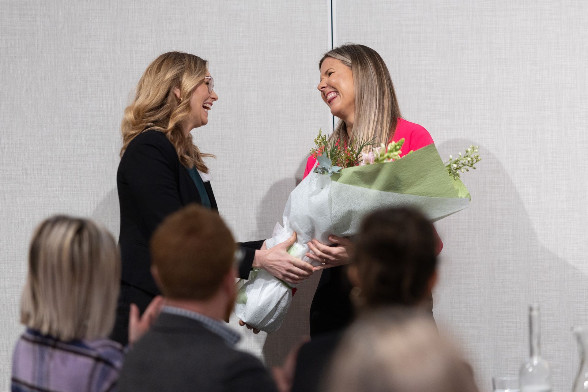 Two women are standing next to each other holding a bouquet of flowers.