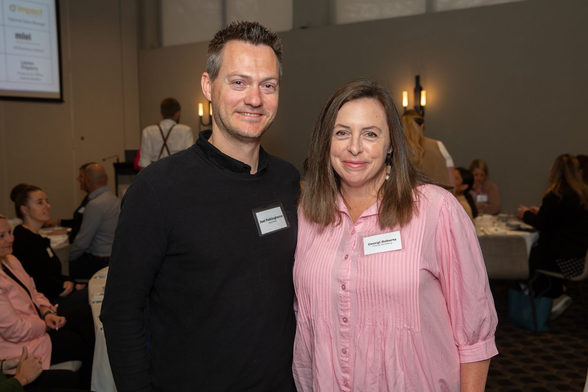 A man and a woman are posing for a picture at a conference.