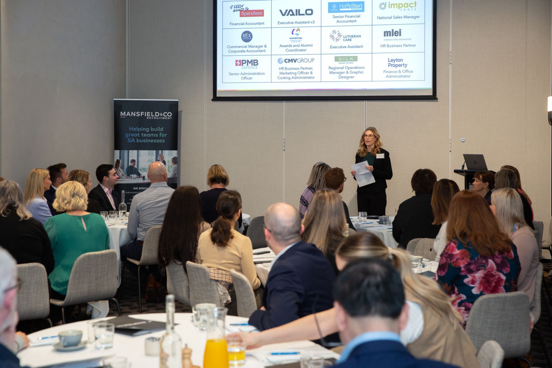 A woman is giving a presentation to a group of people at a conference.