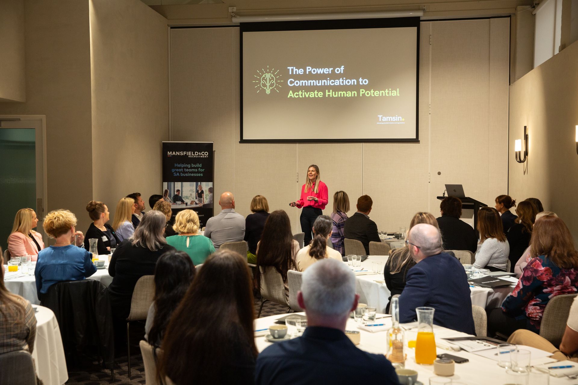 A woman is giving a presentation to a group of people at a conference.