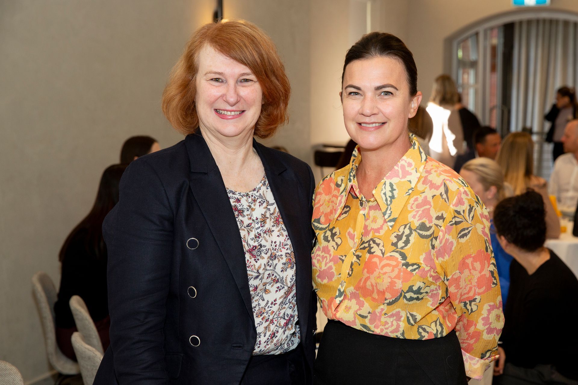 Two women are posing for a picture together in a room.