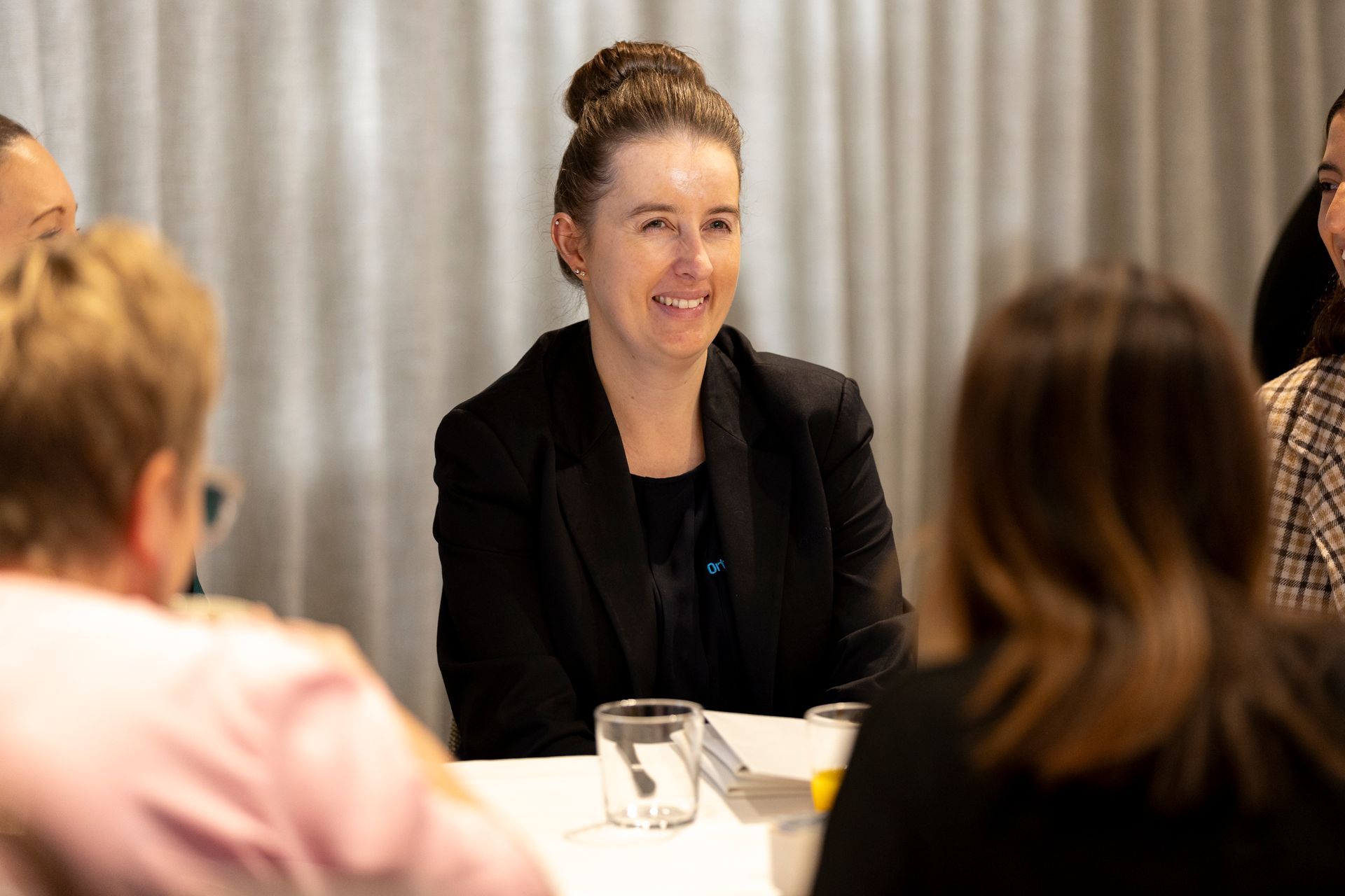 A woman is sitting at a table talking to a group of people.