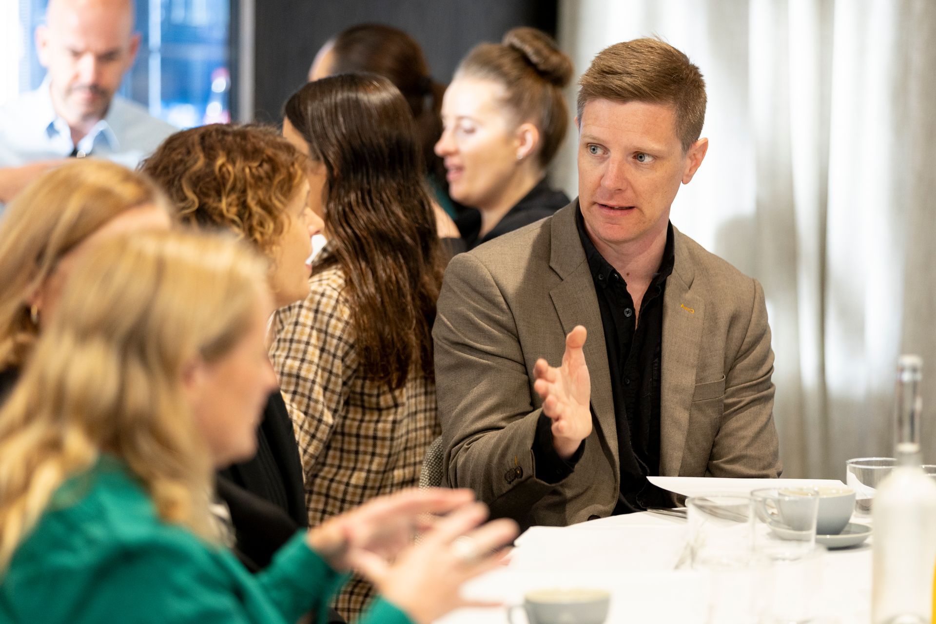 A group of people are sitting at a table talking to each other.