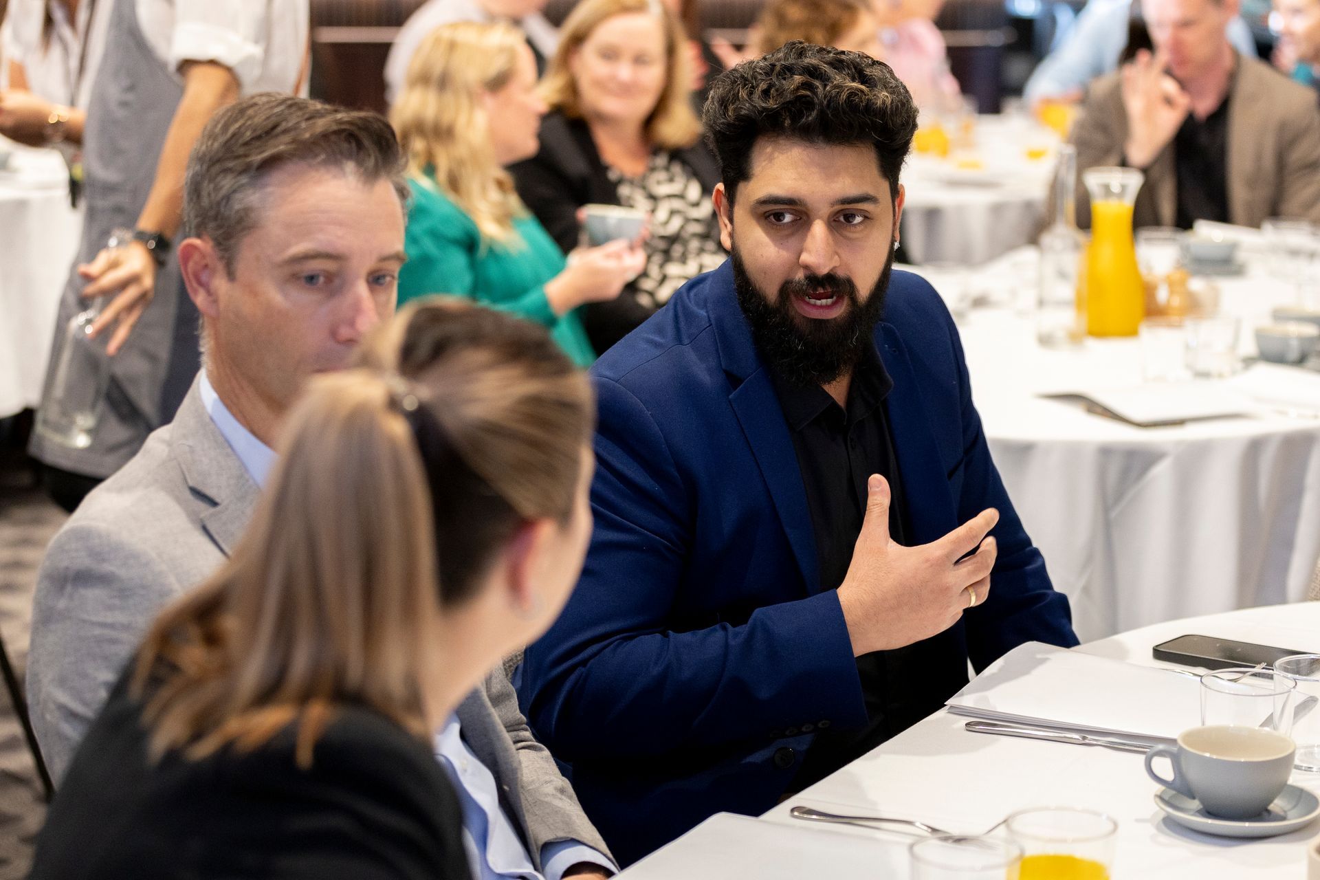 A man in a suit is sitting at a table talking to a woman.