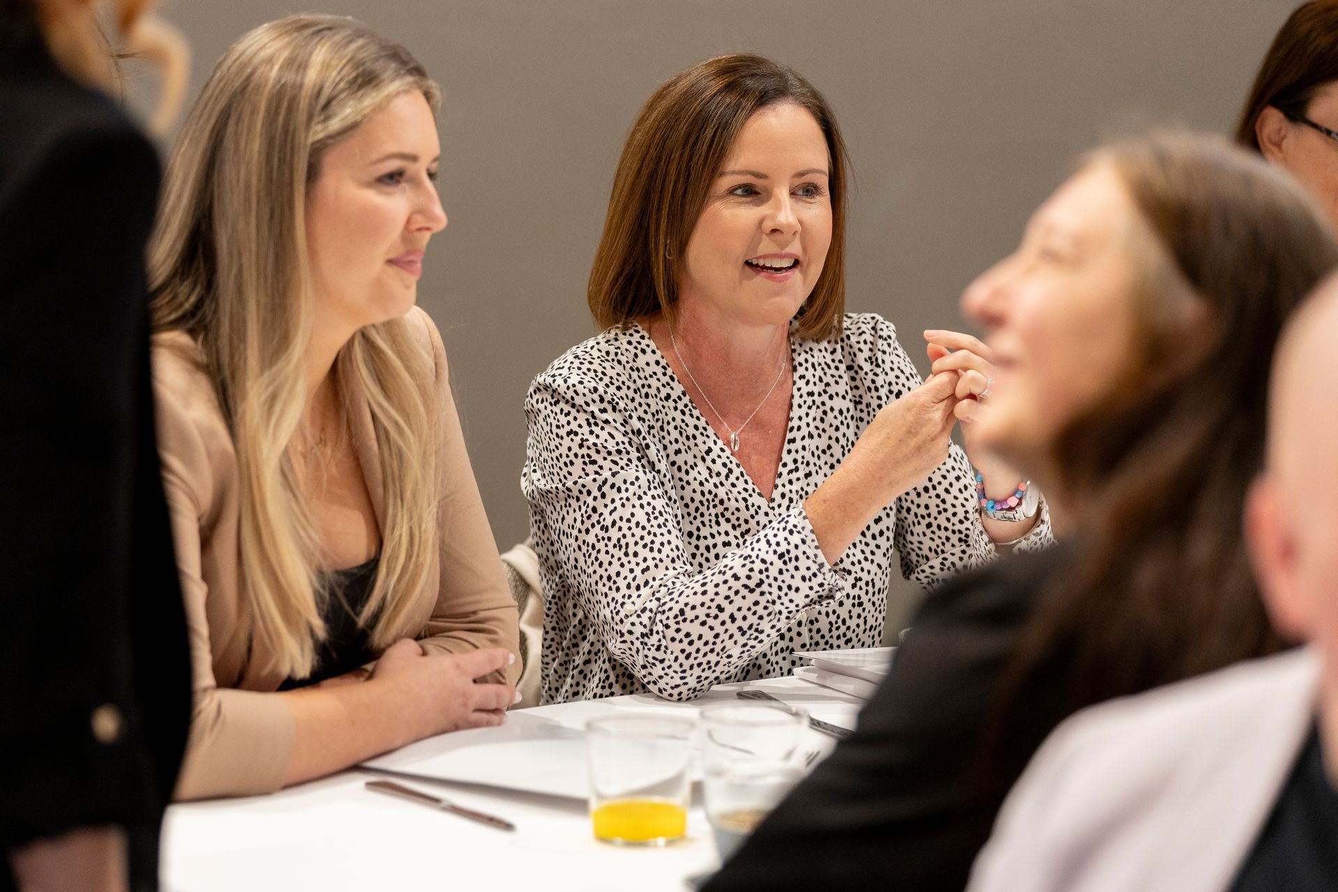 A group of women are sitting at a table talking to each other.