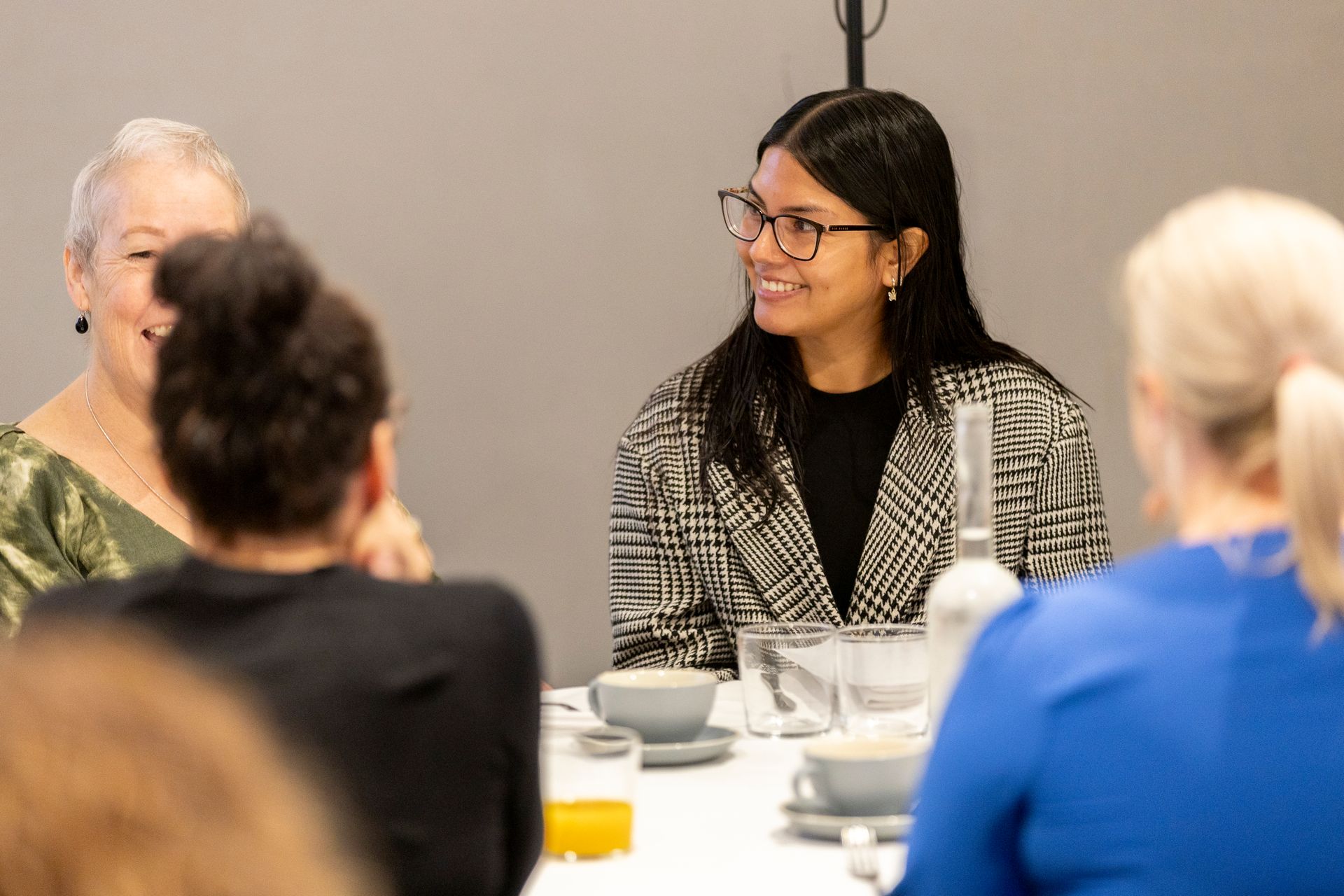 A group of women are sitting at a table talking to each other.