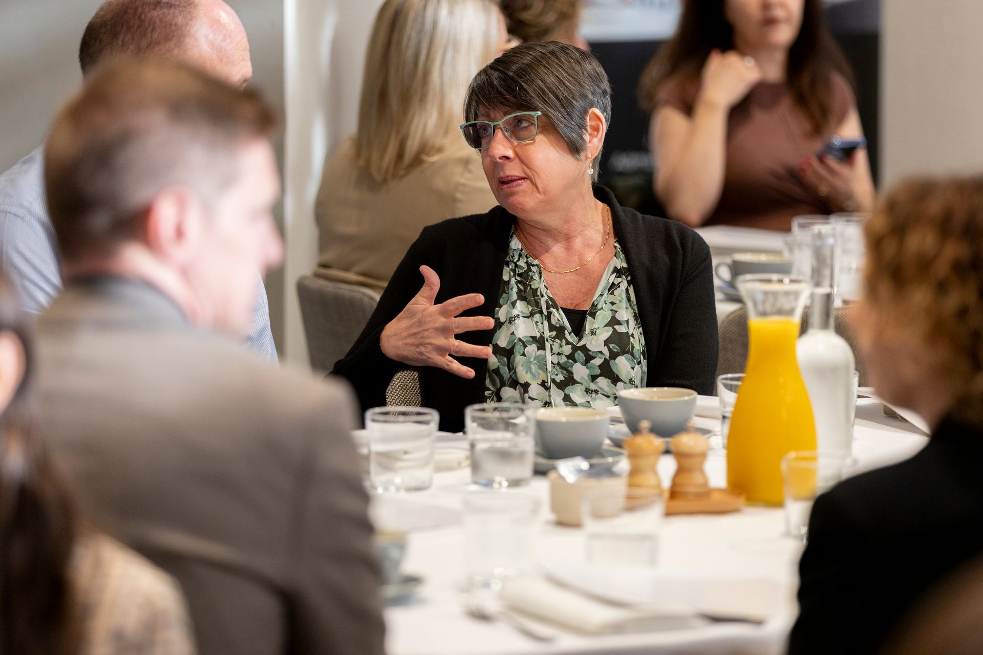 A woman is sitting at a table talking to a group of people.