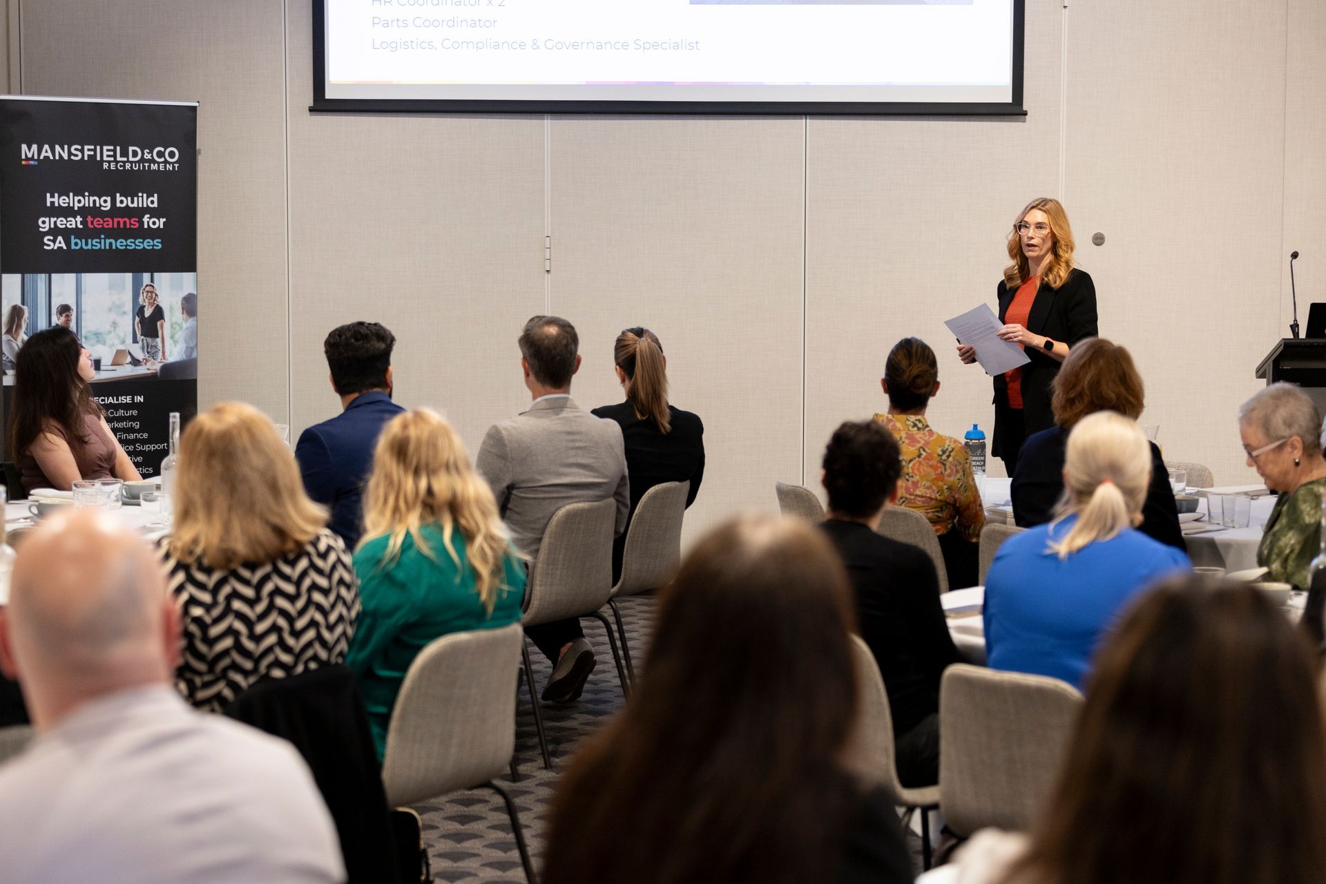 A woman is giving a presentation to a group of people sitting in chairs.