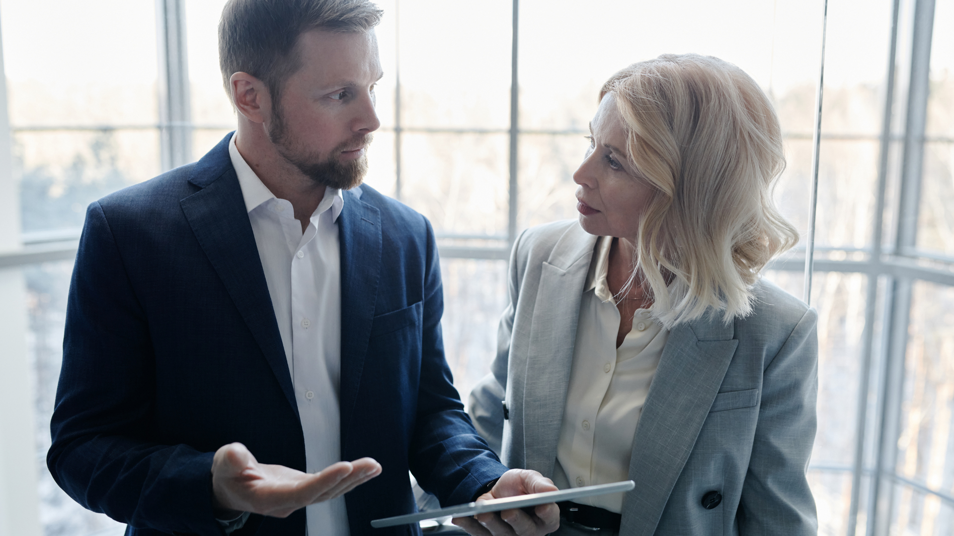 A man and a woman are standing next to each other looking at a tablet.