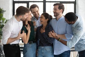 A group of people are hugging each other and laughing in an office.