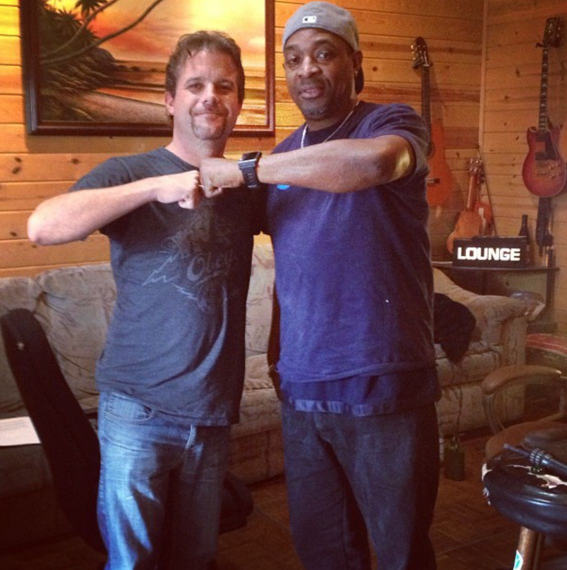 two men are posing for a picture in front of a lounge sign