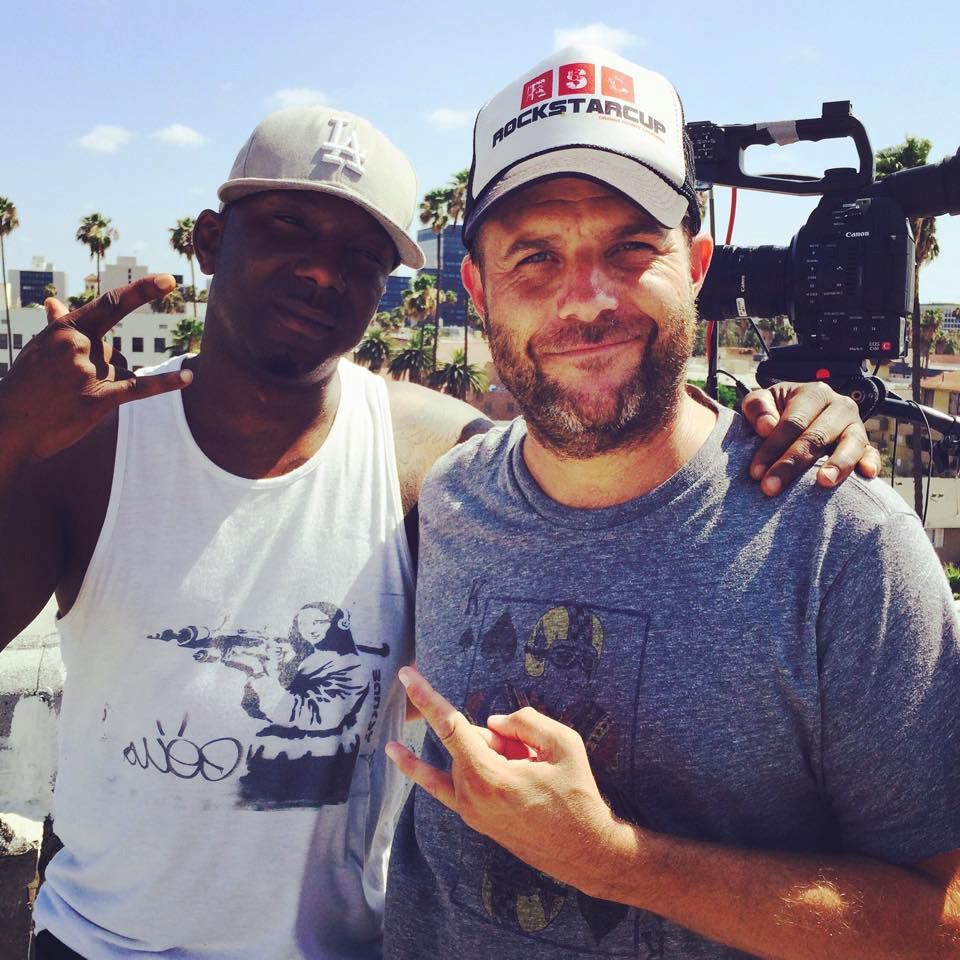 a man wearing a hat that says rockstarcup stands next to another man