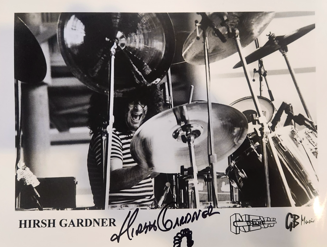 A black and white photo of a man playing drums signed by hirsh gardner