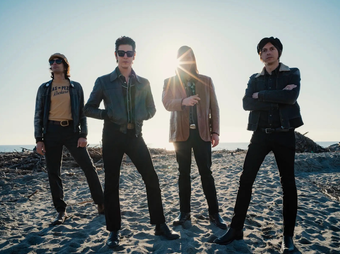 A group of men are standing on a sandy beach.