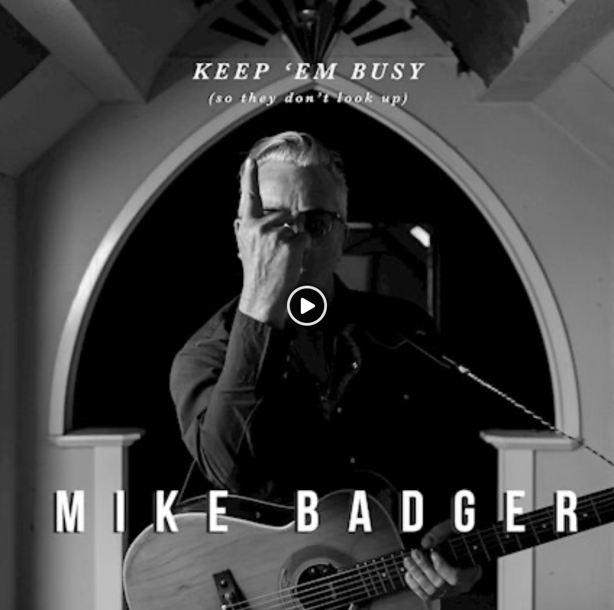 A black and white photo of mike badger playing a guitar