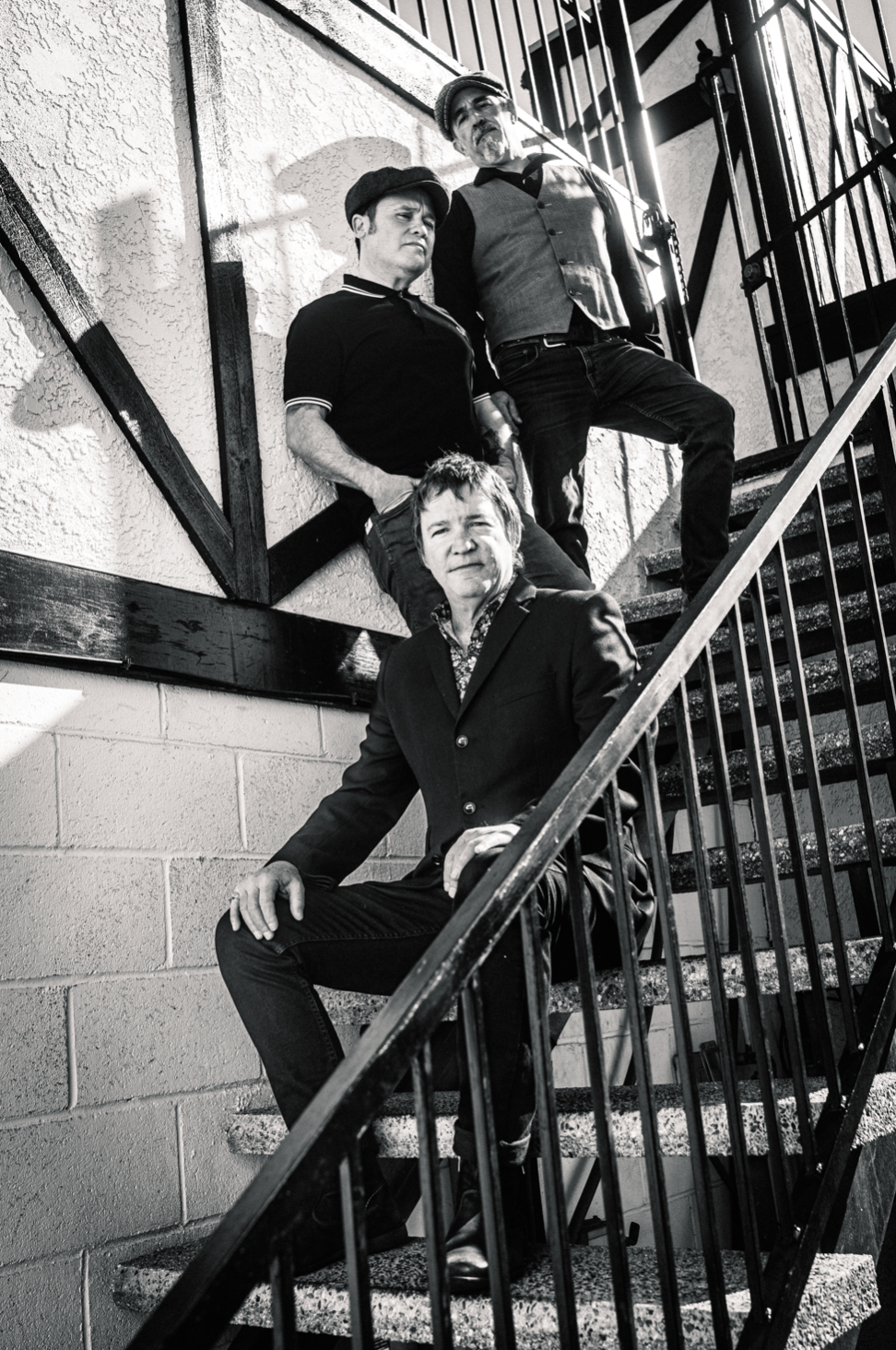 Three men are sitting on a set of stairs in a black and white photo.