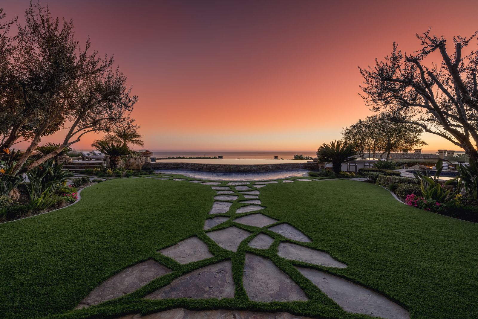 A stone walkway leading to the ocean at sunset