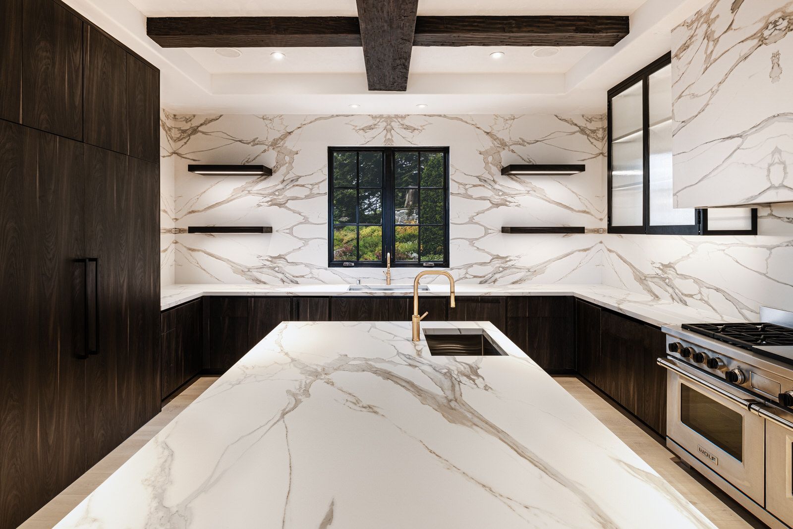 A kitchen with marble counter tops , stainless steel appliances , and a large island.