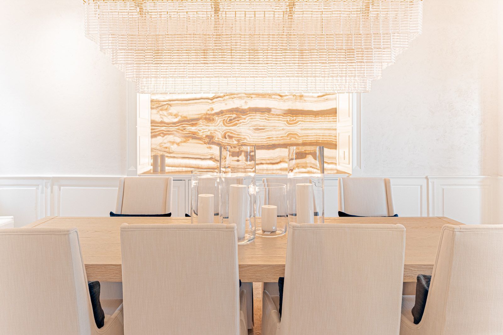 A dining room with a long table and chairs and a large chandelier.