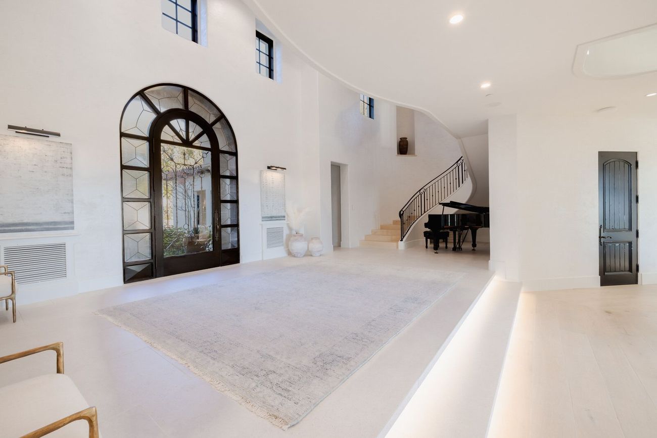 A large luxury entrance room with a piano and stairs.