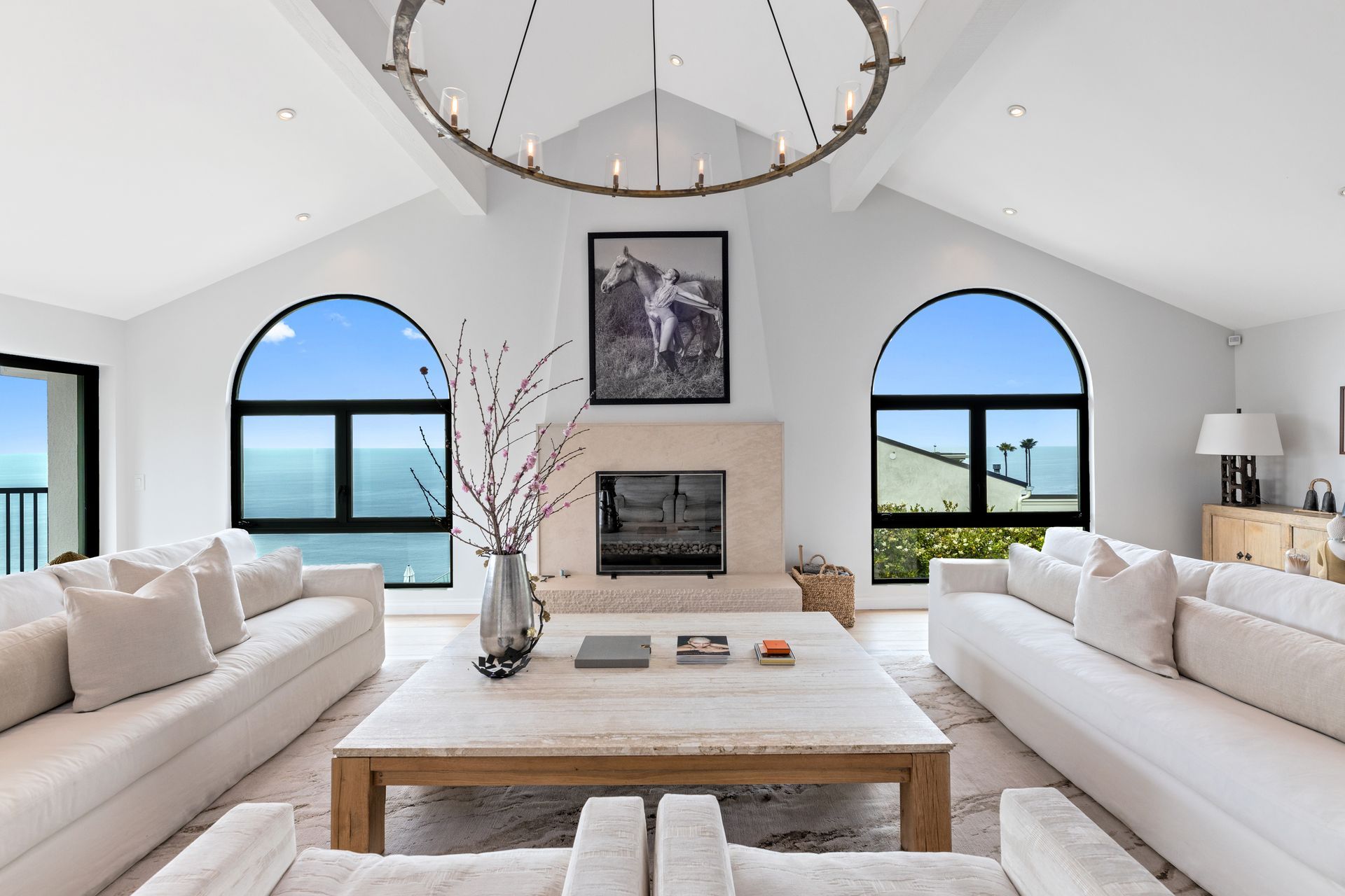 A living room filled with furniture and a fireplace with a view of the ocean.