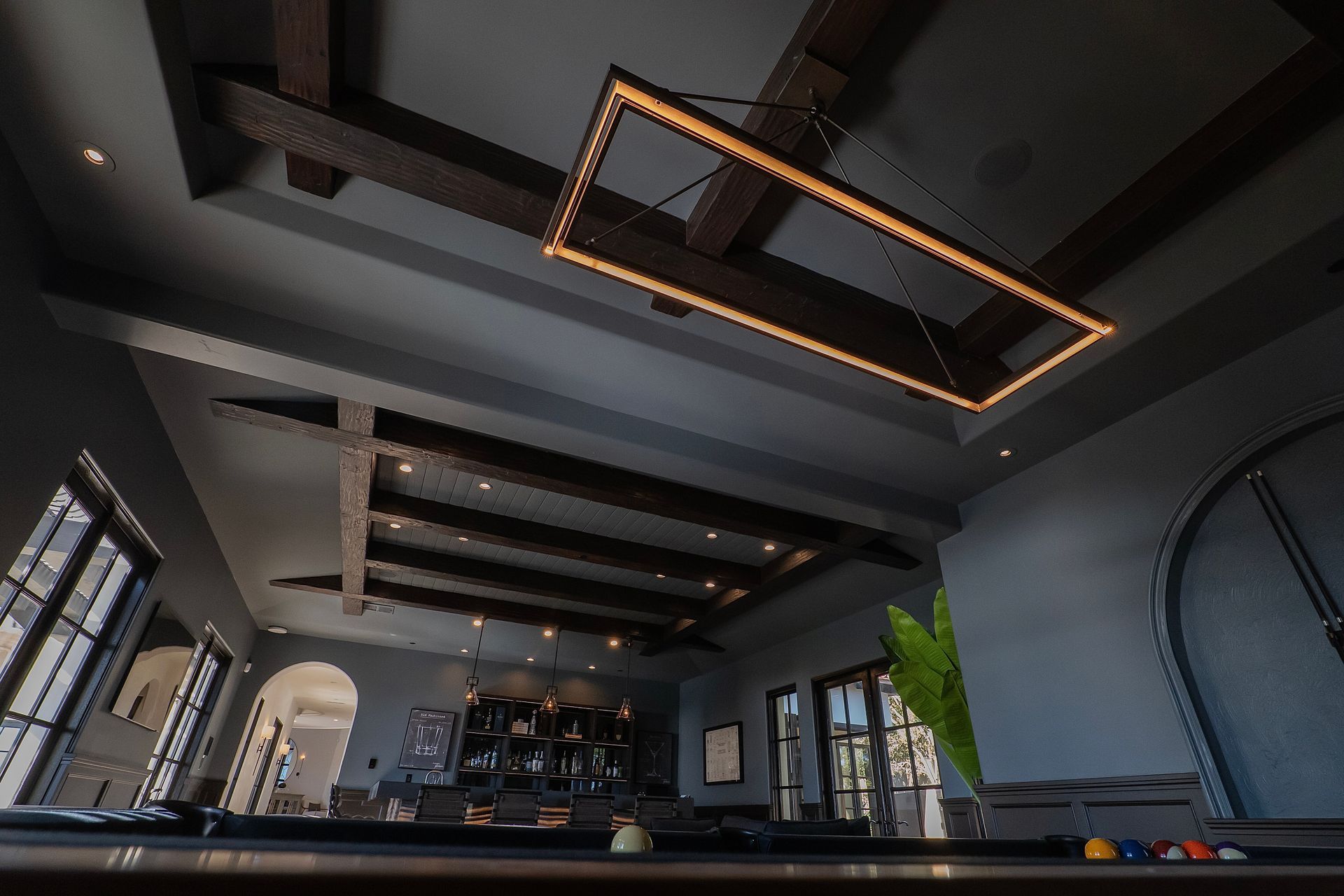 A large room with a pool table and a chandelier hanging from the ceiling.
