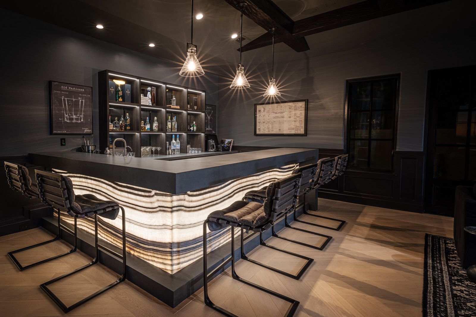 A bar with a long counter and stools in a dark room.