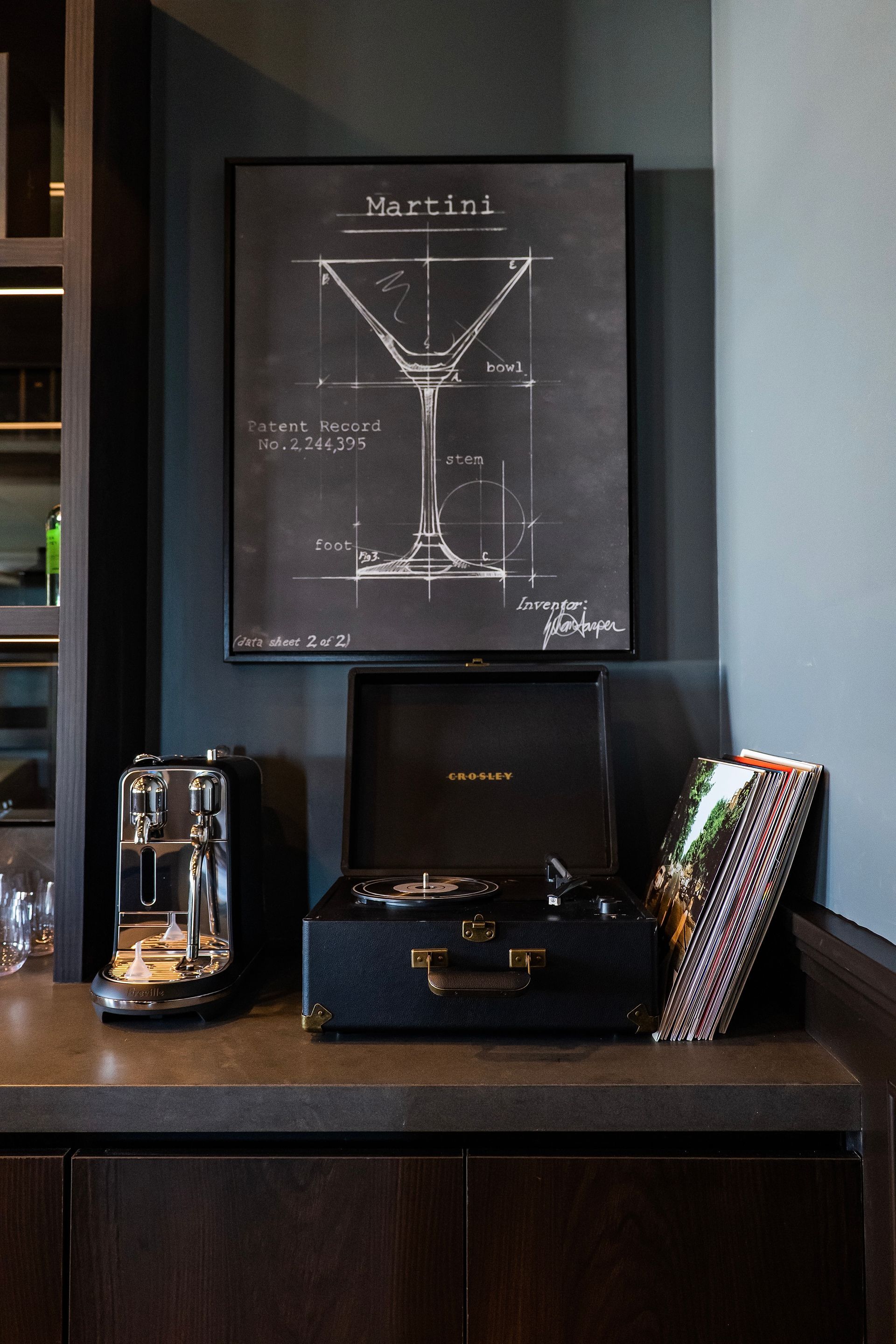 A picture of a martini glass is on a wall above a record player