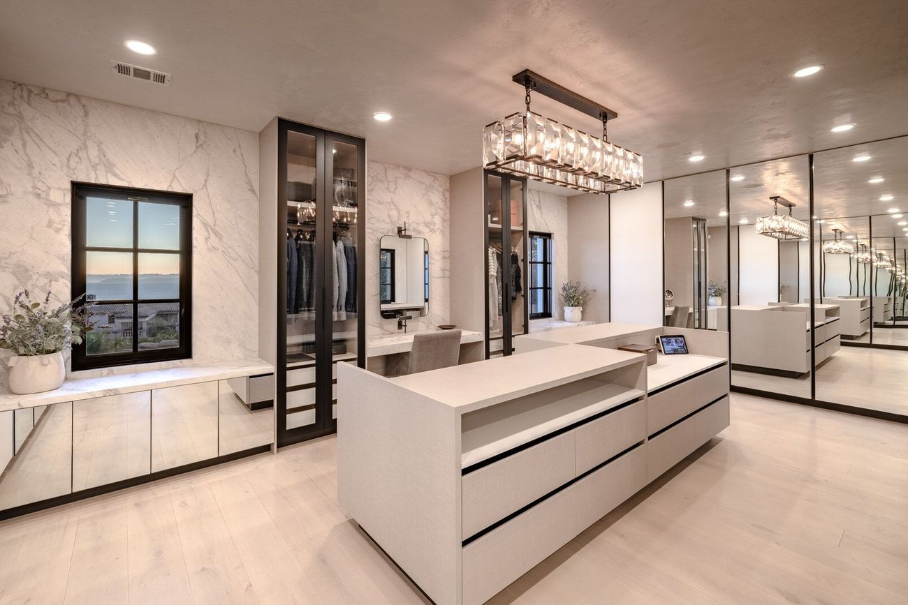 A large walk in closet with a large island in the middle of the room.