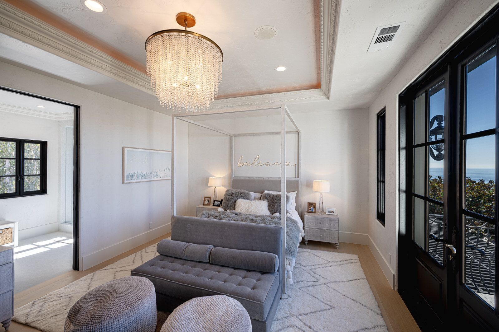 A bedroom with a canopy bed and a chandelier hanging from the ceiling.