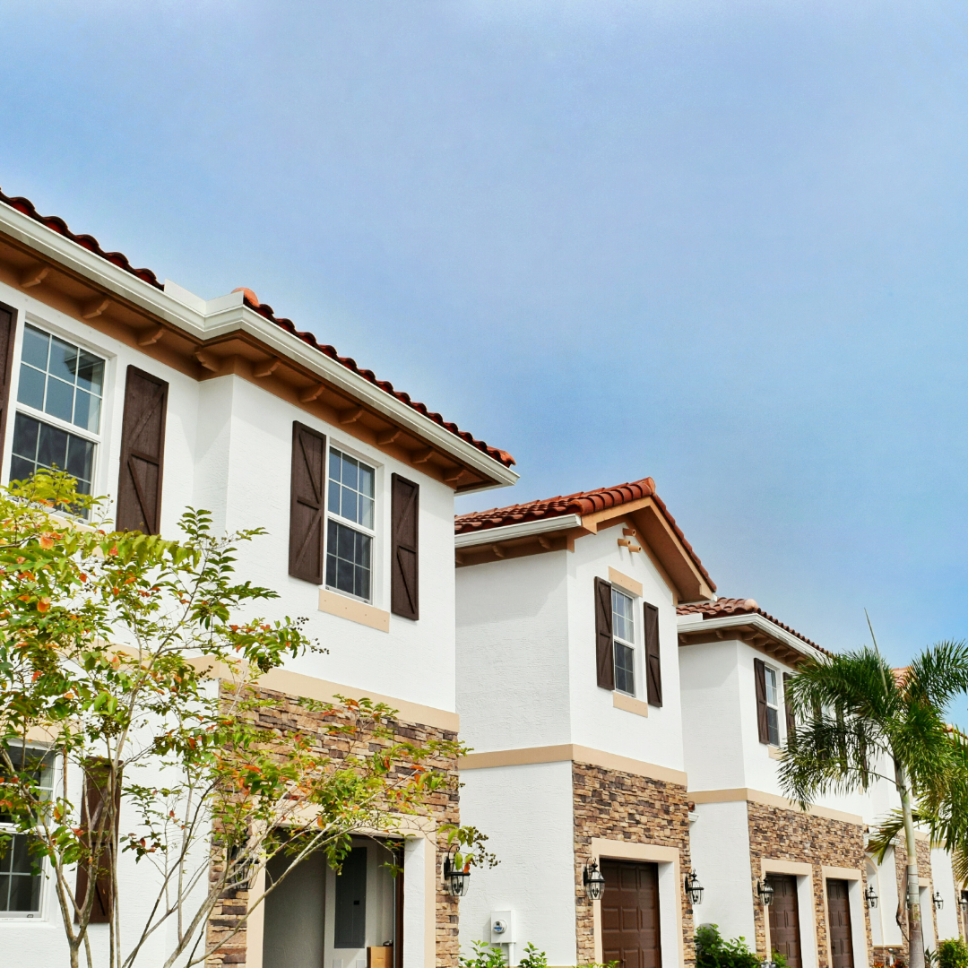 A row of white houses with brown shutters on the windows