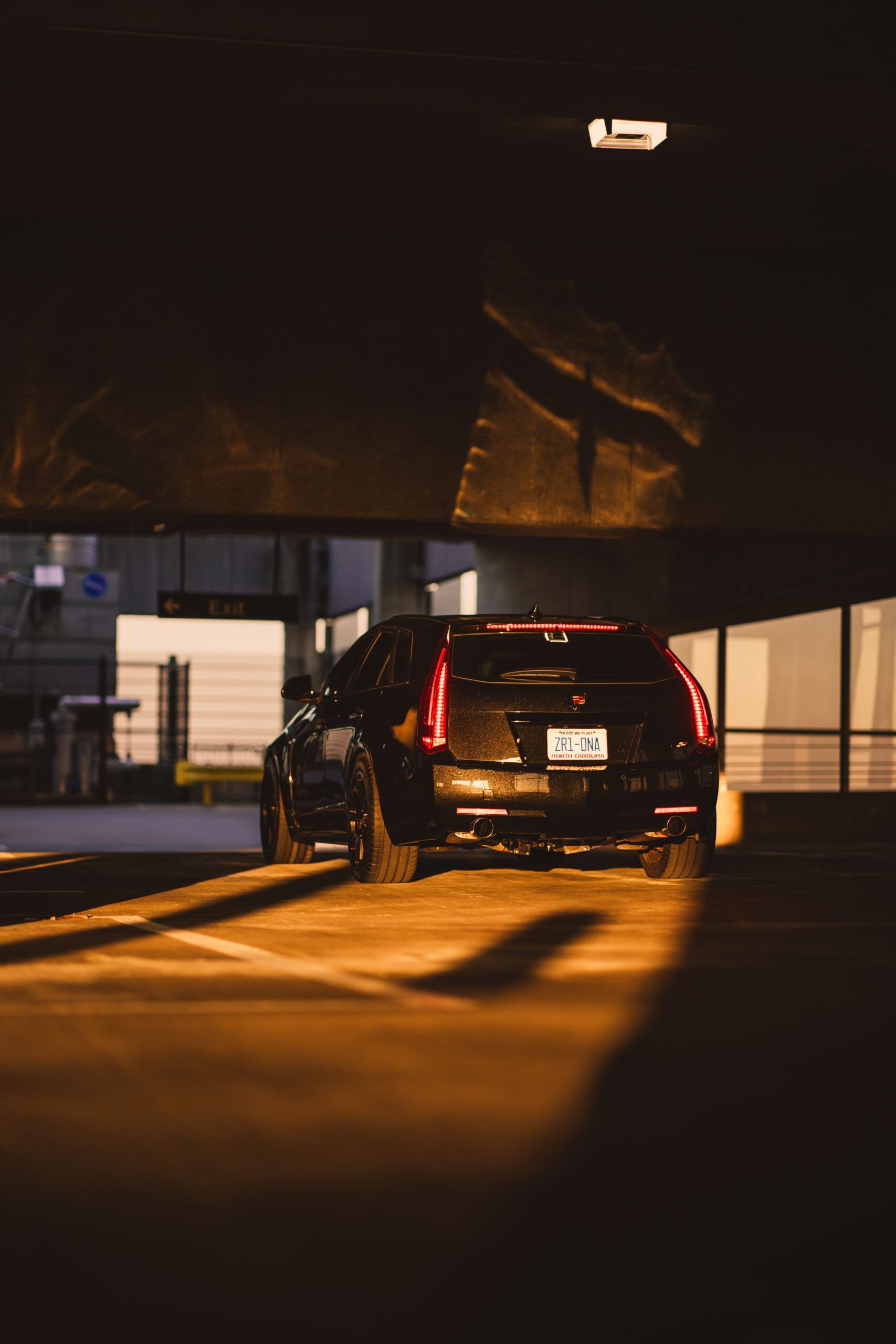 Woman speaking on stage with a microphone, holding papers. A man with a guitar stands behind her.