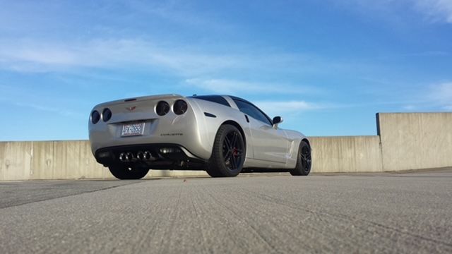 A silver Chevrolet Corvette parked on a concrete rooftop with a blue sky in the background.