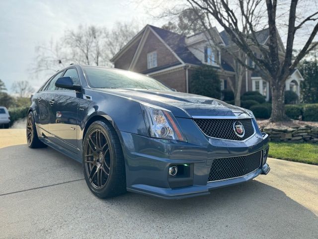 A dark blue Cadillac CTS-V sports sedan parked in a suburban driveway on a sunny day.