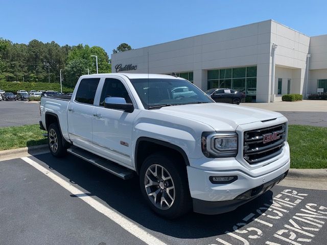 A white GMC pickup truck parked in a dealership lot on a sunny day.