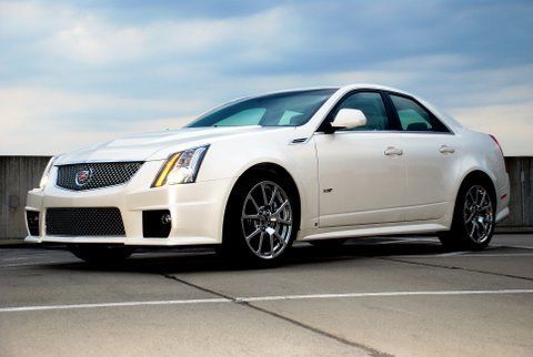 A white Cadillac CTS-V sedan parked on an empty concrete parking lot under a cloudy sky.