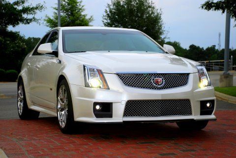 A white Cadillac CTS-V sports sedan parked on a red brick driveway.