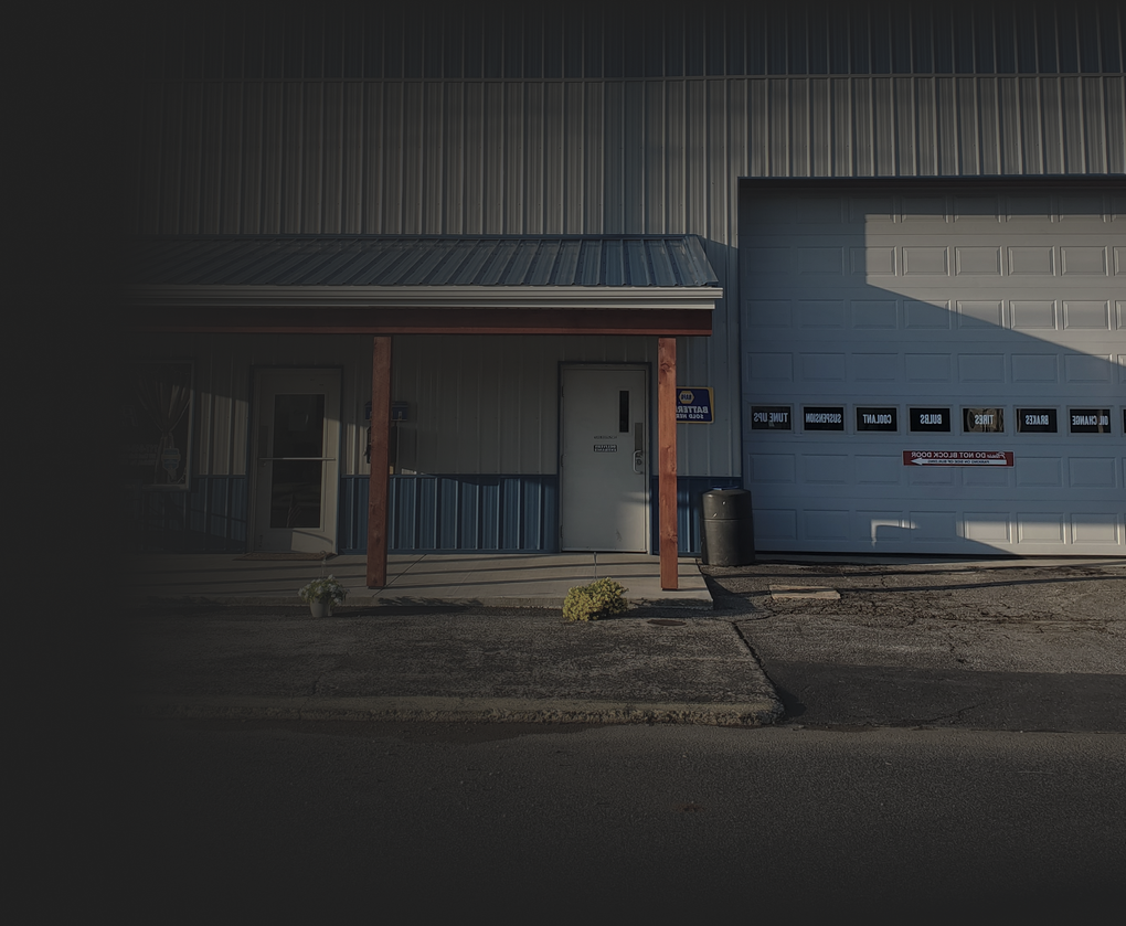 Building exterior with a small porch, door, and large garage door. Gray metal siding.
