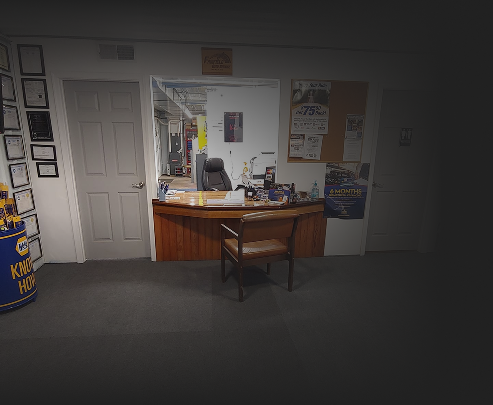 A cluttered office reception area with a desk, chair, and door.