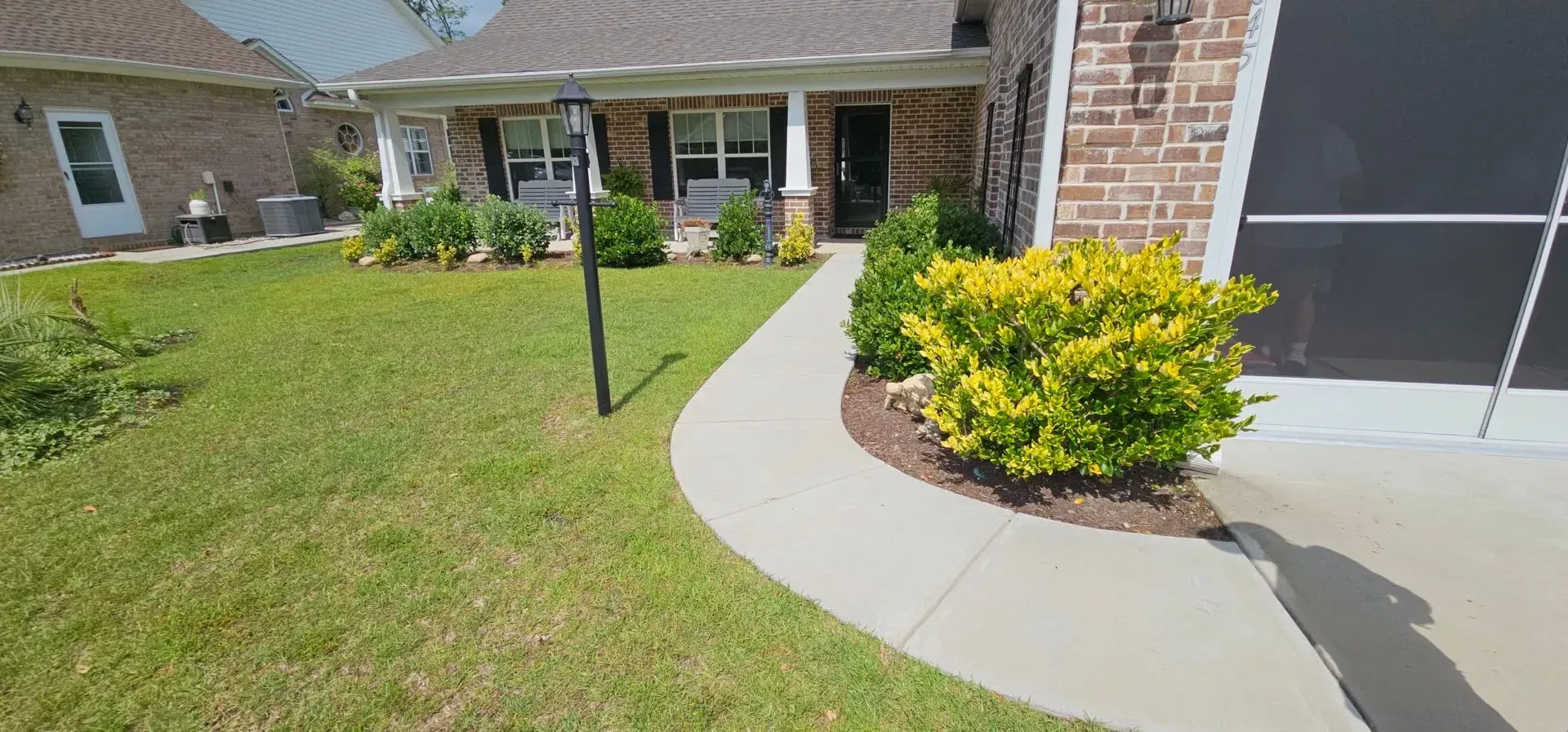 A house with a brick facade, green lawn, and a sidewalk leading to the front door.