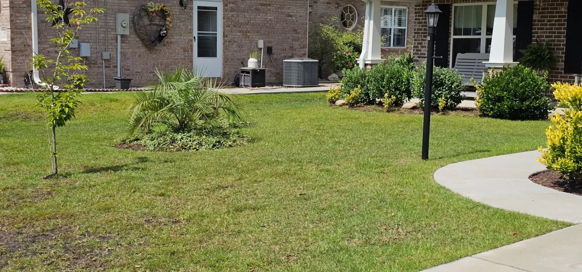 Green lawn with a sidewalk leading to a house.