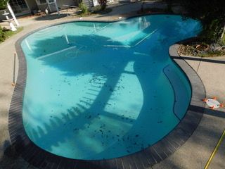 An aerial view of a large swimming pool in a backyard.