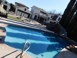 A large swimming pool is in the backyard of a house