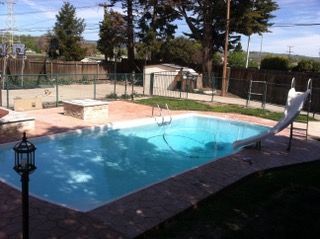 A large swimming pool with a slide in the backyard