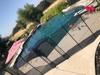 A man is swimming in a pool behind a fence.