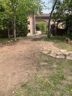 Un chemin de terre menant à une maison entourée d'arbres et d'herbe.