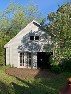 Un garage blanc est entouré d'arbres et d'herbe.