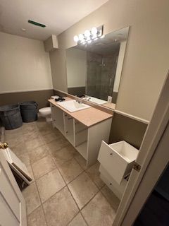 Une salle de bain avec un lavabo, des toilettes, un miroir et des tiroirs.