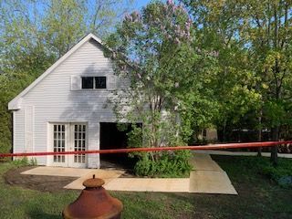 Une maison blanche est entourée de paperasse et d'arbres.