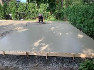 Un homme travaille sur une allée en béton dans une cour arrière.